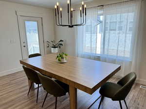 Dining space featuring a chandelier, baseboards, healthy amount of natural light, and light wood-style flooring
