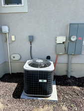 Exterior view of central AC, electric meter, and stucco siding