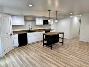 Kitchen with butcher block countertops, black appliances, a sink, light wood-type flooring, and recessed lighting