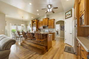 Kitchen featuring a breakfast bar, arched walkways, solid cherry cabinetry, ceiling fan, and tasteful backsplash