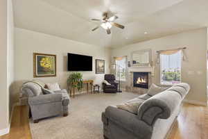 Living area featuring a high end fireplace, baseboards, ceiling fan, and light wood finished floors