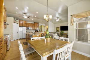 Dining space with arched walkways, light wood-style flooring, a ceiling fan, recessed lighting, and vaulted ceiling