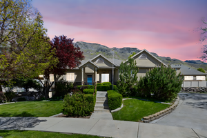 View of front facade featuring a mountain view, stucco, stone siding and a front yard