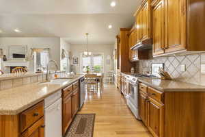 Kitchen with stainless steel dishwasher, a sink, solid cherry cabinetry, and gas stove
