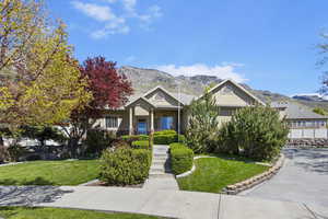 Craftsman-style house with a mountain view, stucco siding, and a front lawn