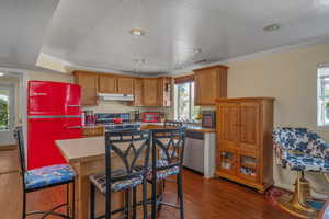 Kitchen featuring gas range, under cabinet range hood, dishwasher, fridge, and wood finished floors