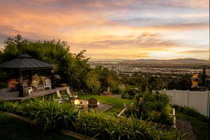 Yard at dusk featuring an outdoor fire pit, a gazebo, a deck with mountain view, and fence