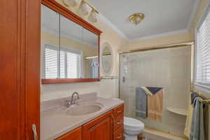 Full bath with a shower stall, vanity, ornamental molding, and toilet