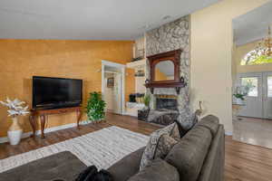 Living area featuring wood finished floors, a fireplace, a chandelier, and baseboards