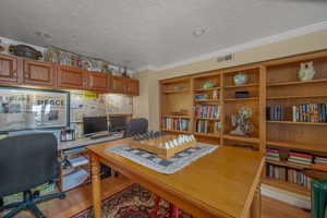 Office featuring light wood-style floors, crown molding, and a textured ceiling
