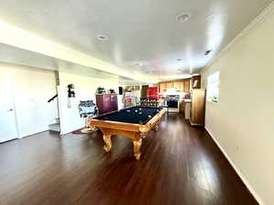 Game room with pool table, dark wood-style floors, crown molding, and baseboards