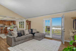 Living room with light wood-style flooring, ornamental molding, lofted ceiling, and baseboards