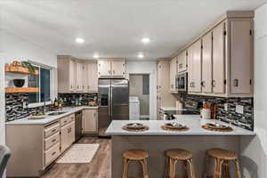 Kitchen with stainless steel appliances, a sink, a peninsula, dark wood finished floors, and washer / dryer