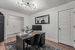 Office space with wood finished floors, a chandelier, baseboards, and a textured ceiling