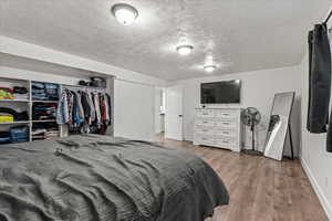 Bedroom featuring baseboards, a textured ceiling, and wood finished floors
