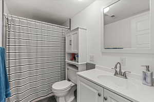 Bathroom with vanity, toilet, and curtained shower