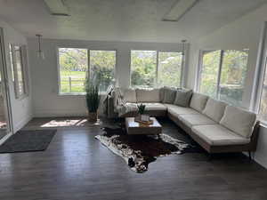 Sunroom / solarium featuring vaulted ceiling, wood-type flooring, baseboards, and a wooden deck