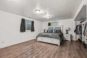 Bedroom featuring a textured ceiling, wood finished floors, and baseboards