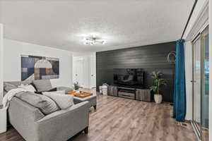 Living room with wood finished floors, a chandelier, and a textured ceiling
