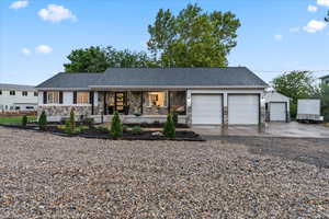 Ranch-style home with stone siding, covered porch, an attached garage, driveway, and roof with shingles