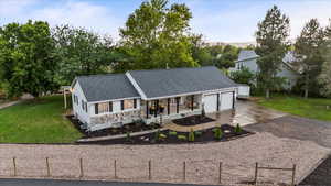 View of front facade with driveway, an attached garage, a porch, and roof with shingles