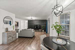 Dining space with a chandelier, an accent wall, wood finished floors, and a textured ceiling