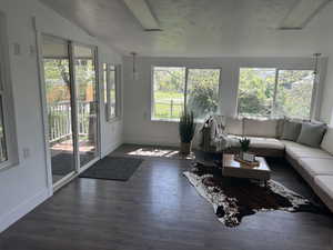 Sunroom / solarium with healthy amount of natural light, lofted ceiling, baseboards, and hardwood / wood-style floors