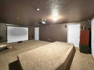 Carpeted home theater featuring a textured ceiling and baseboards