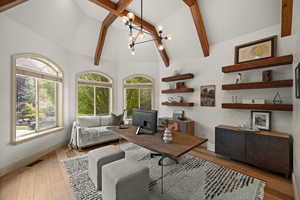 Office space featuring a chandelier, light wood-style flooring, beam ceiling, and high vaulted ceiling