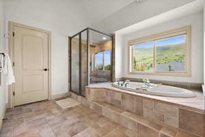 Full bath featuring a stall shower, a bath, stone finish floors, and baseboards