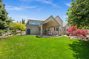 Rear view of house with stucco siding, a patio area, and roof with shingles