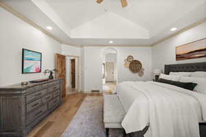 Bedroom with arched walkways, recessed lighting, light wood-style floors, ceiling fan, and vaulted ceiling