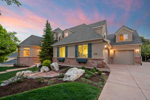 View of front of house with brick siding, roof with shingles, concrete driveway, stucco siding, and an attached garage