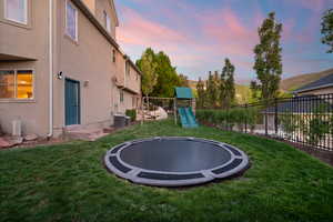 Yard at dusk featuring a trampoline and cooling unit