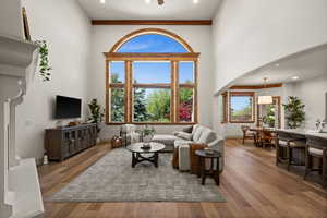 Living room featuring arched walkways, hardwood / wood-style floors, baseboards, and a high ceiling