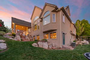 Rear view of property featuring a yard, stucco siding, and central AC unit