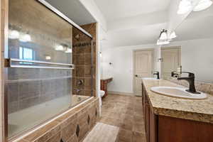 Bathroom with double vanity, toilet, tiled shower / bath combo, and baseboards