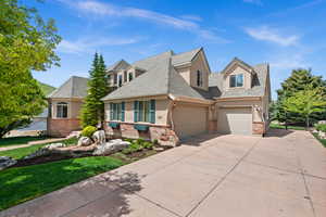 View of front of property with stucco siding, driveway, brick siding, fence, and a shingled roof