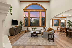 Living room with arched walkways, wood-type flooring, and a towering ceiling