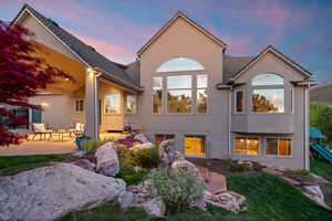 Back of house featuring a patio area, stucco siding, and a lawn