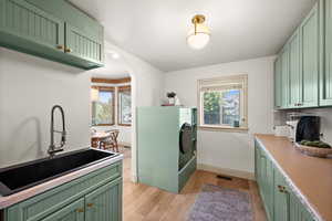 Clothes washing area featuring baseboards, light wood-type flooring, arched walkways, and washer / clothes dryer
