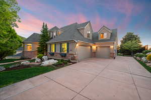 View of front of house featuring brick siding, concrete driveway, stucco siding, and an attached garage