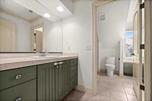 Bathroom featuring vanity, baseboards, ornamental molding, toilet, and tile patterned floors