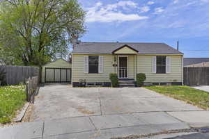 Bungalow-style house featuring a garage, fence, an outdoor structure, a chimney, and a shingled roof
