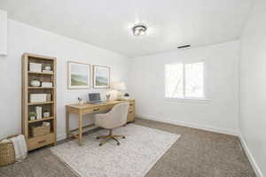 Office area with dark colored carpet and baseboards