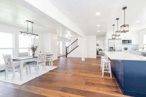 Kitchen featuring pendant lighting, dark wood-style floors, a kitchen breakfast bar, stainless steel appliances, and tasteful backsplash