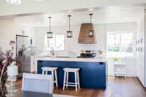 Kitchen featuring appliances with stainless steel finishes, premium range hood, light countertops, tasteful backsplash, and recessed lighting