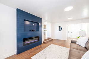 Living area with a large fireplace, baseboards, and wood finished floors