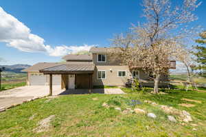 View of front of house with a garage, driveway, a front lawn, a mountain view, and a shingled roof