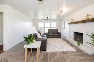 Living room with a ceiling fan, a tile fireplace, and carpet